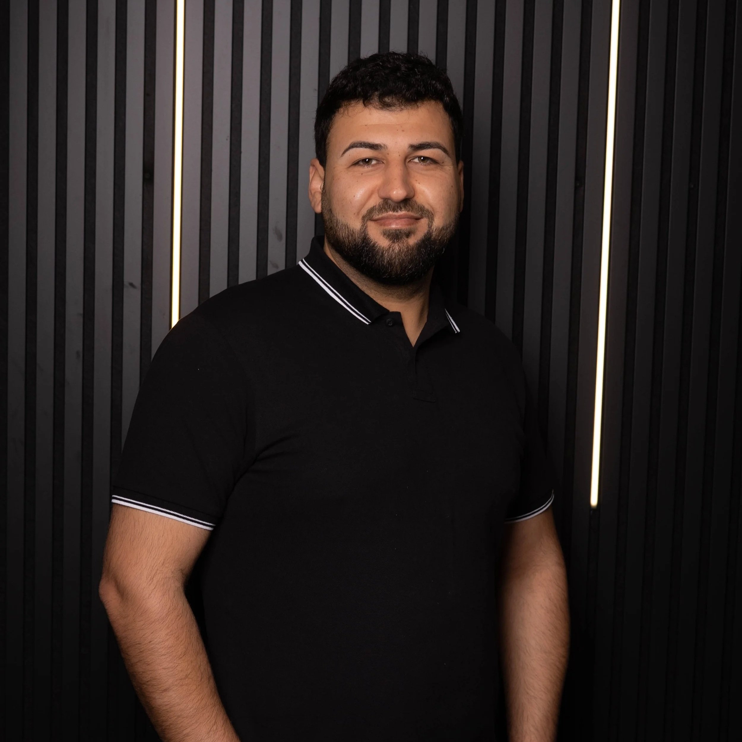 Nawaf, Friseur bei Alsterschnitt in Hamburg vor der Lamellenwand im Salon