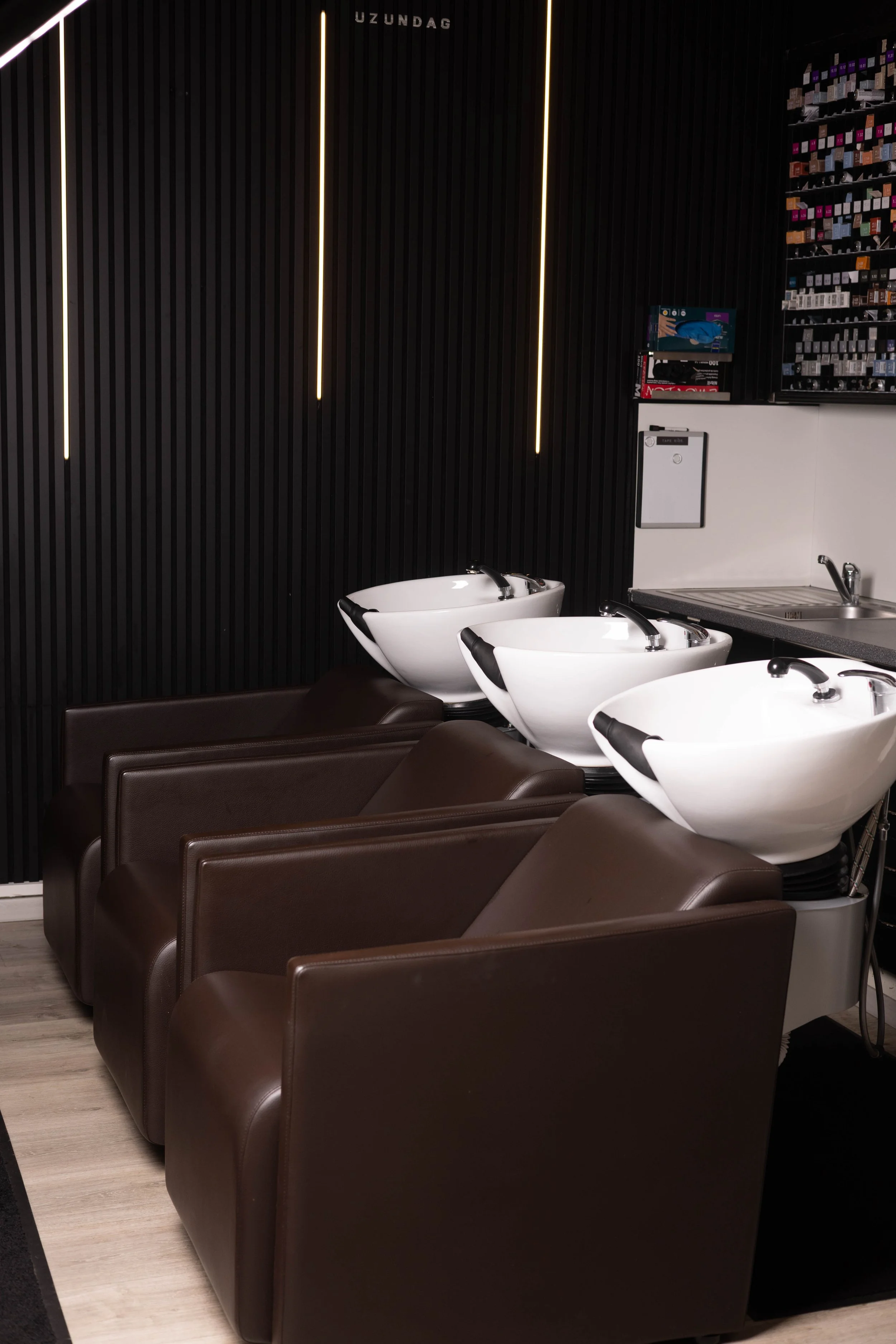 Waschplätze mit Lederstühlen und Farbregal im Friseursalon Alsterschnitt Hamburg