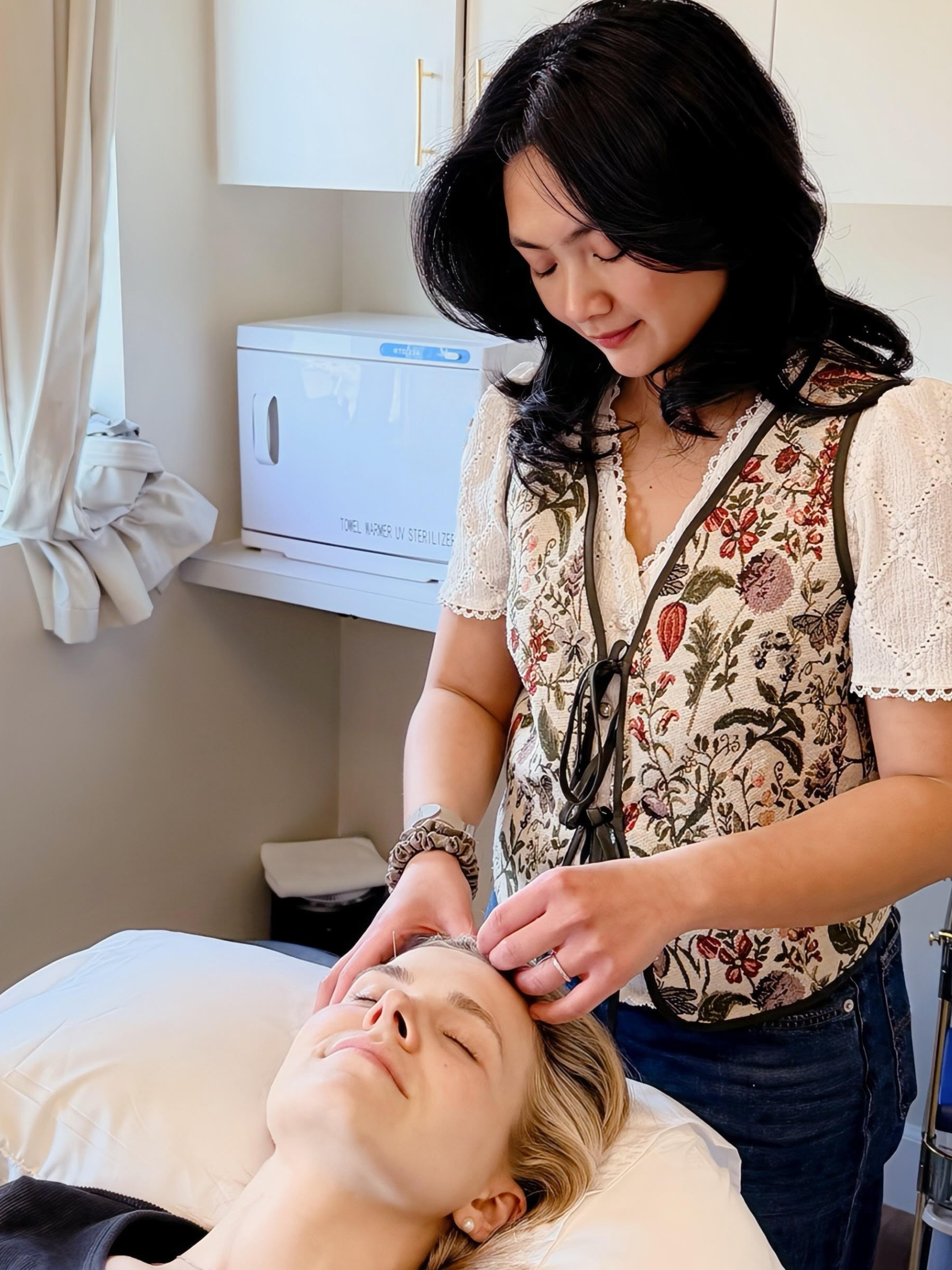 A woman receiving a facial treatment from a professional in a clinical setting.