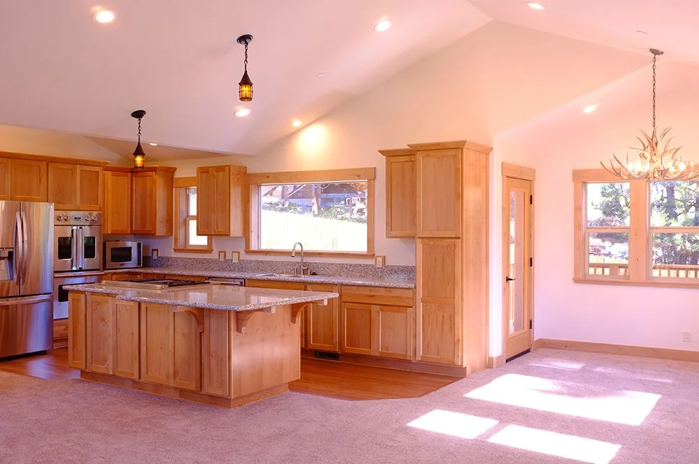 Kitchen and dining area with wooden cabinets, granite countertops, large windows, and hardwood floors.