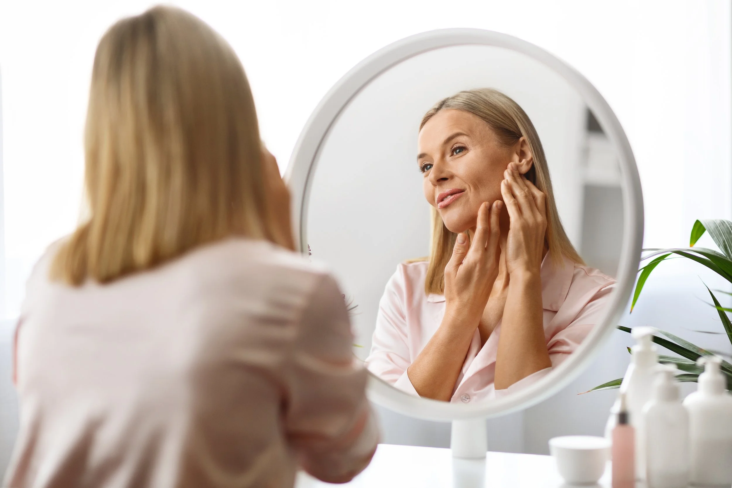 Woman looking in mirror to illustrate skin rejuvenation in Abbotsford