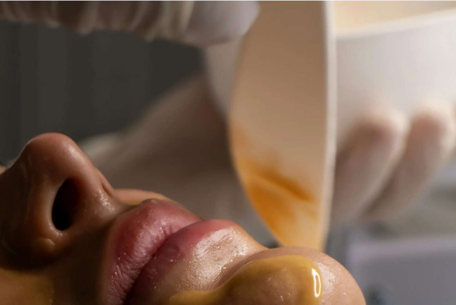 Close-up of a person's face, with caramel sauce being poured onto their lips and chin.