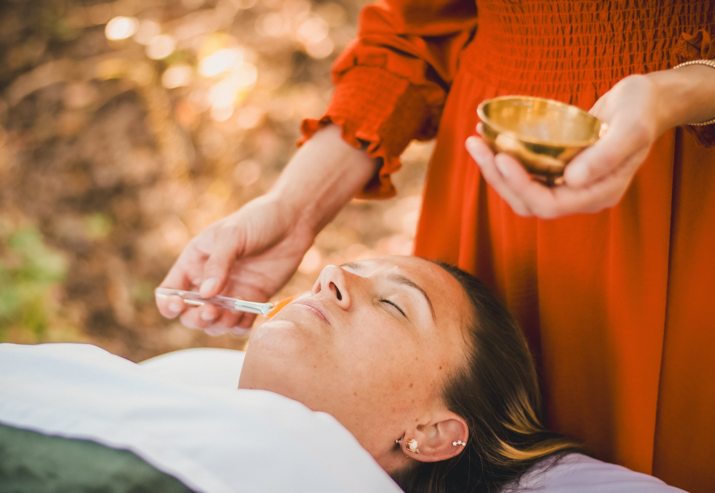 Person receiving an injection in the face outdoors while another person holds a small bowl.