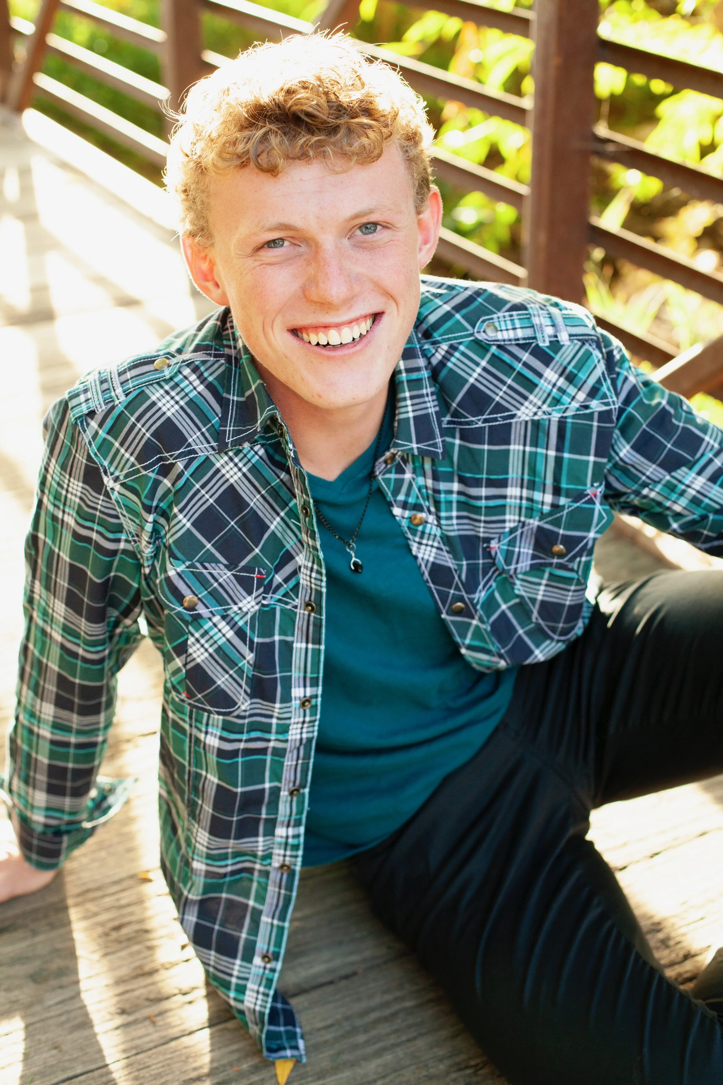 Close-up of a man with short dark hair and stubble, smiling in a bike shop with bike helmets, a mountain bike, and sports gear in the background.