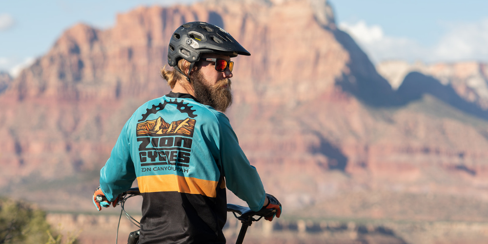 A woman riding a mountain bike on a rocky desert landscape under a clear blue sky.