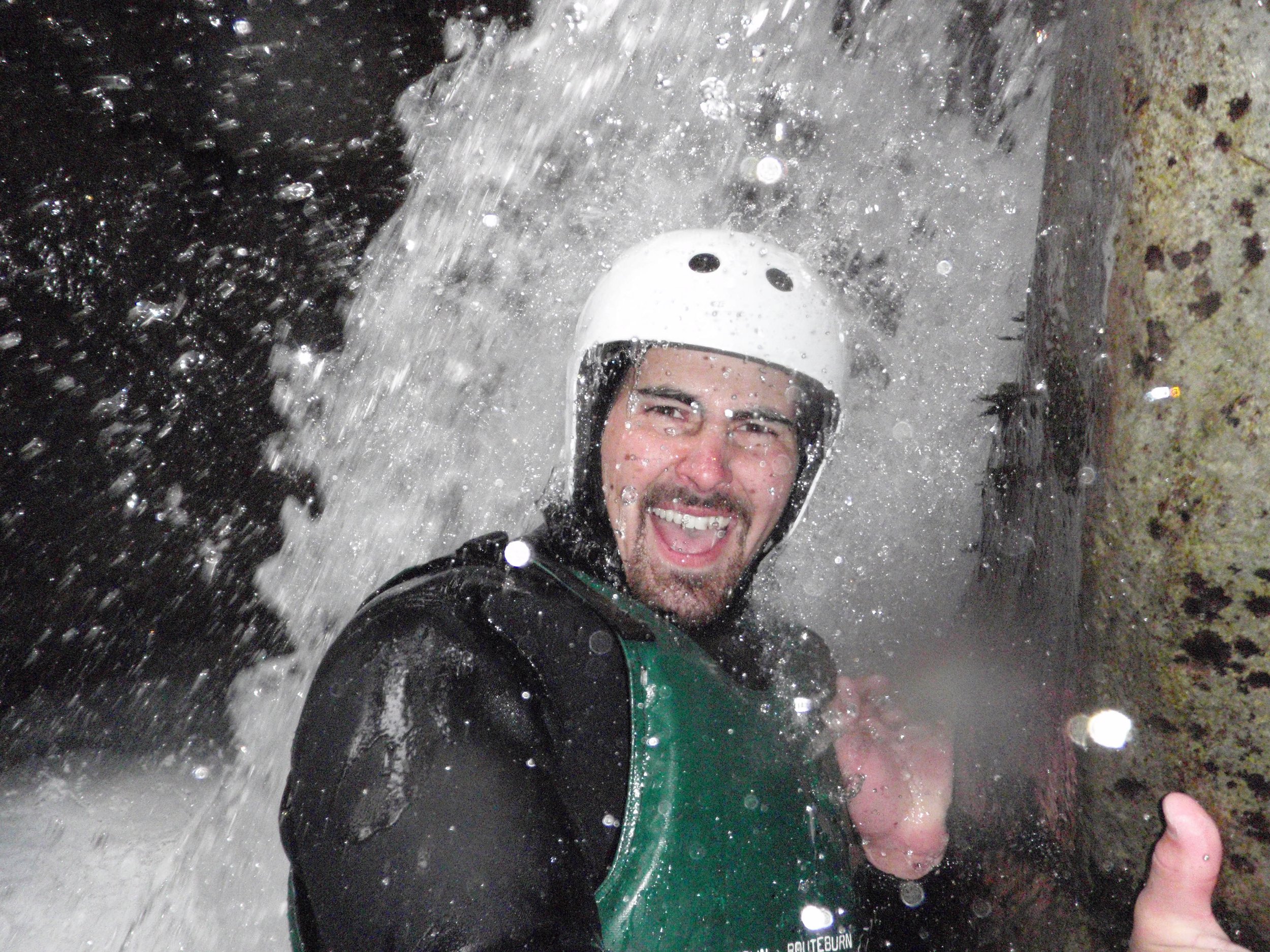 Spencer under a waterfall during Canyoning - New Zealand