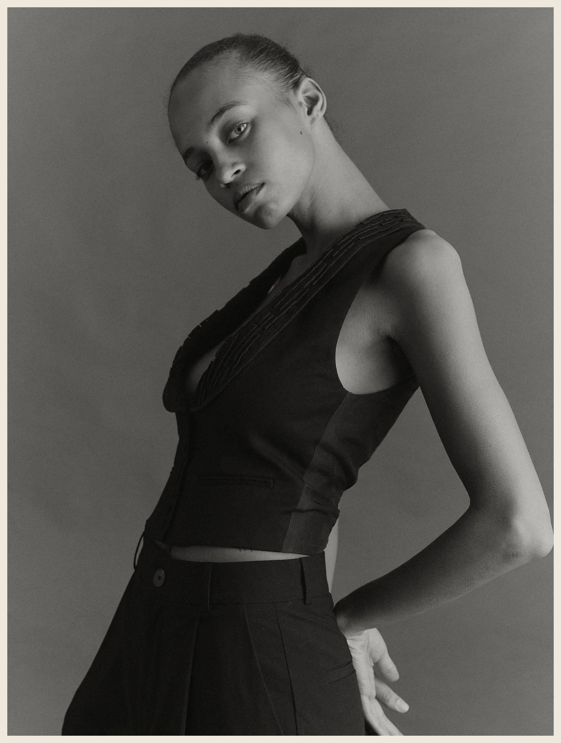 Black and white portrait of a woman with short hair in a sleeveless top, looking slightly over her shoulder.