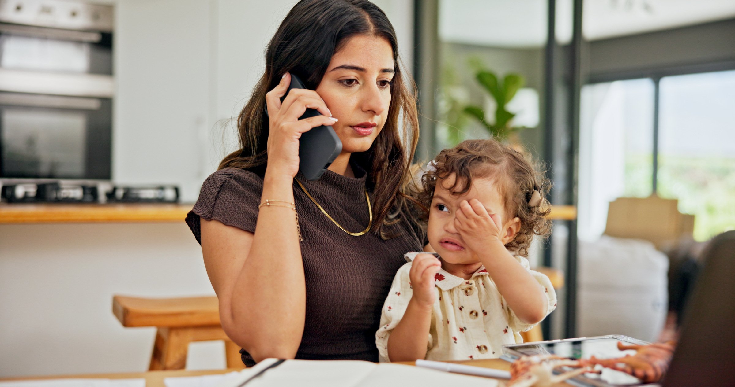 Mother multitasking between work meetings and toddler care