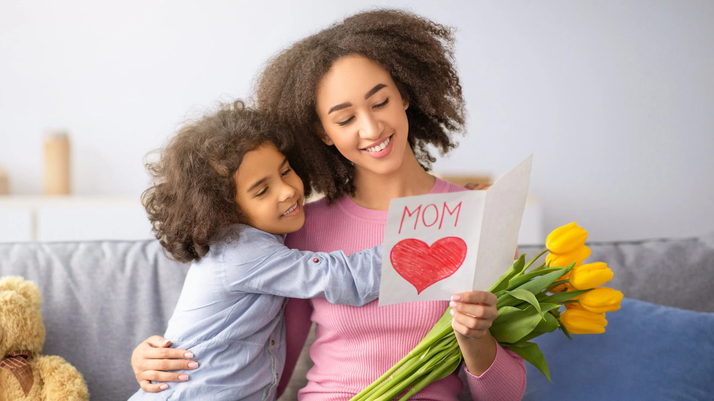 Child hugging her mom and giving flowers on Mother’s Day