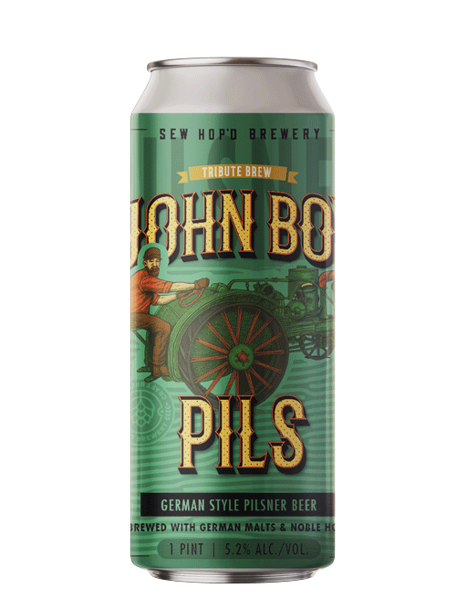 A can of John Boy Pils German style pilsner beer with green and gold packaging, featuring an illustration of a person driving a vintage car.