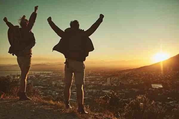 couple celebrating relationship success on top of a mountain