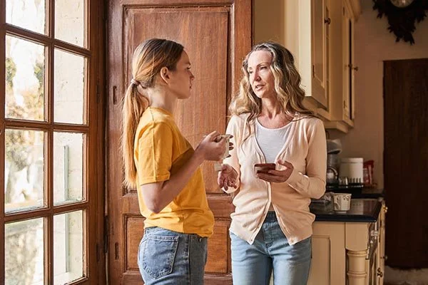 daughter standing with mom serious face and mom calmly looking at her talking