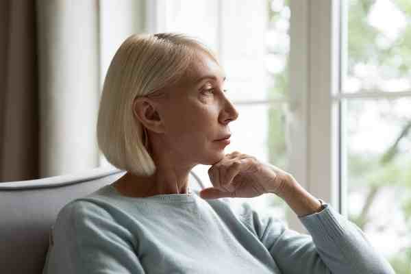 A person sitting quietly by a window, processing betrayal trauma