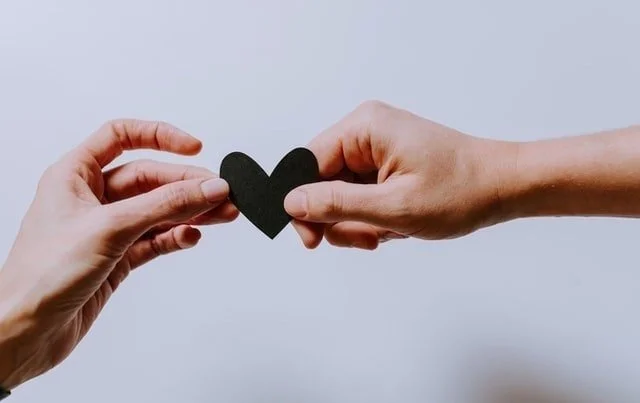 male and female hands passing off a heart between them