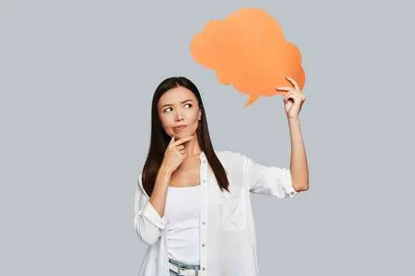 Woman holding a speech bubble, considering whether she needs life coaching or therapy