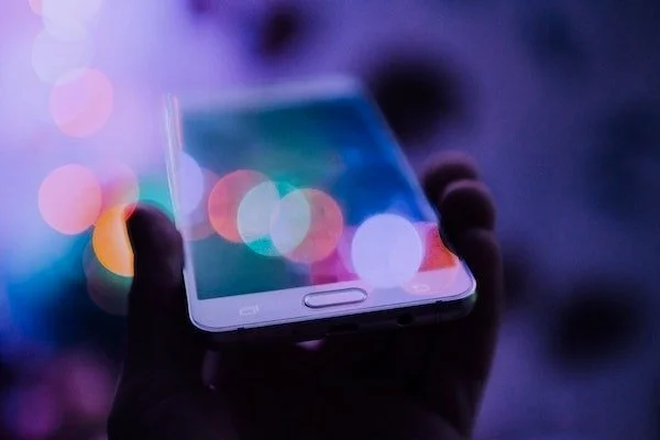 hand holding a cell phone against a blurred background