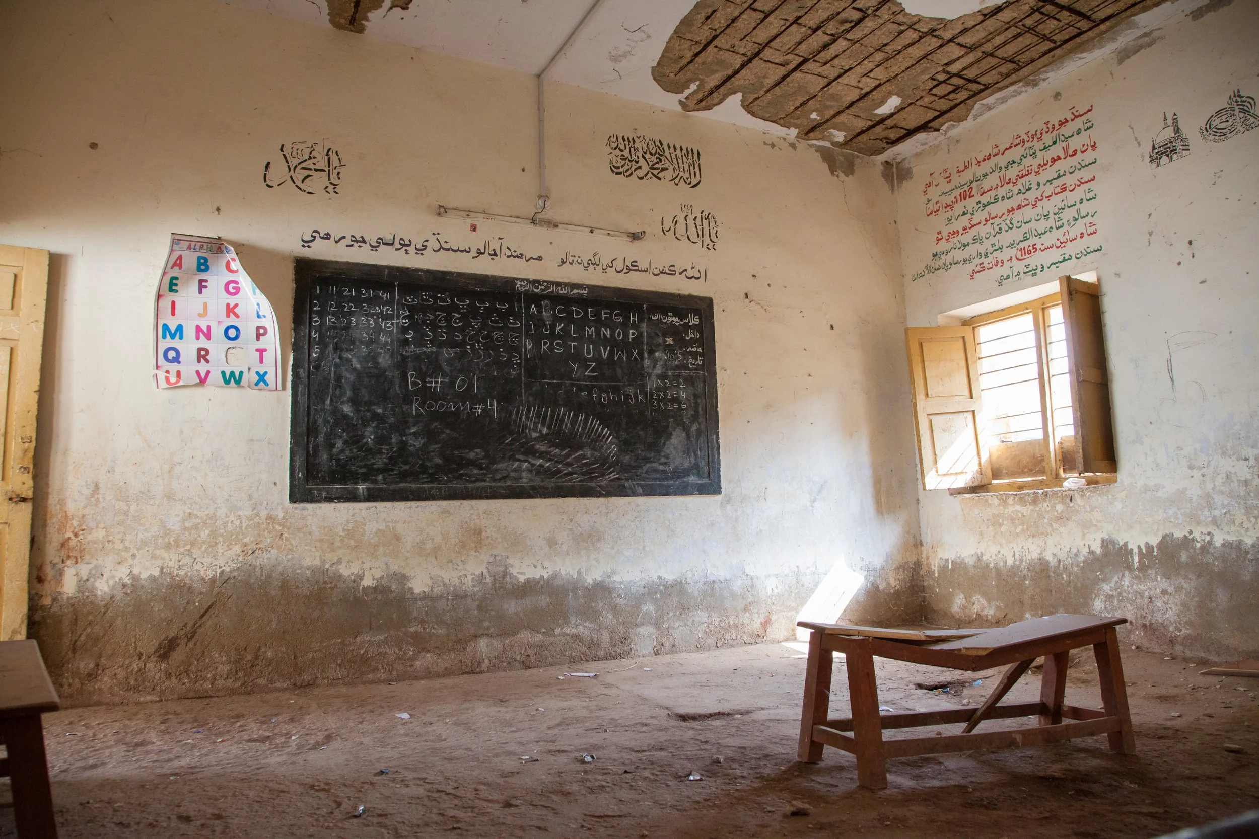 Empty classroom in a low-income school with whiteboard and broken bench