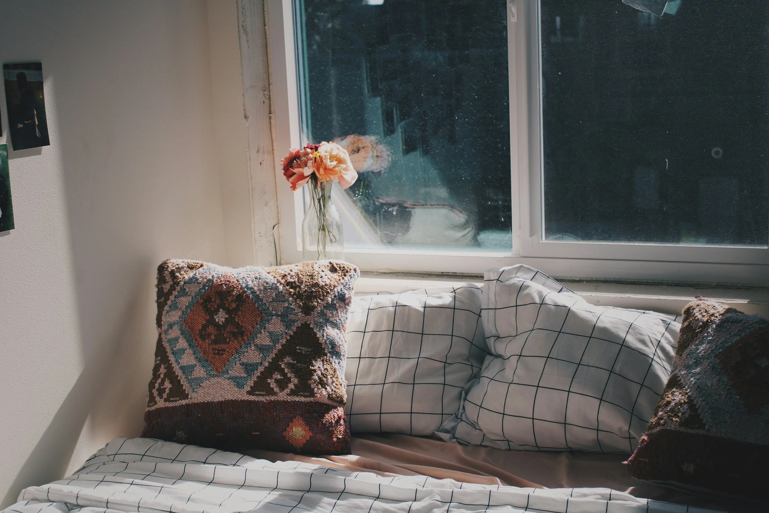 Late afternoon light streaming through a window onto layered cushions and textured fabrics, illustrating how shifting natural light changes the mood and character of a space throughout the day.