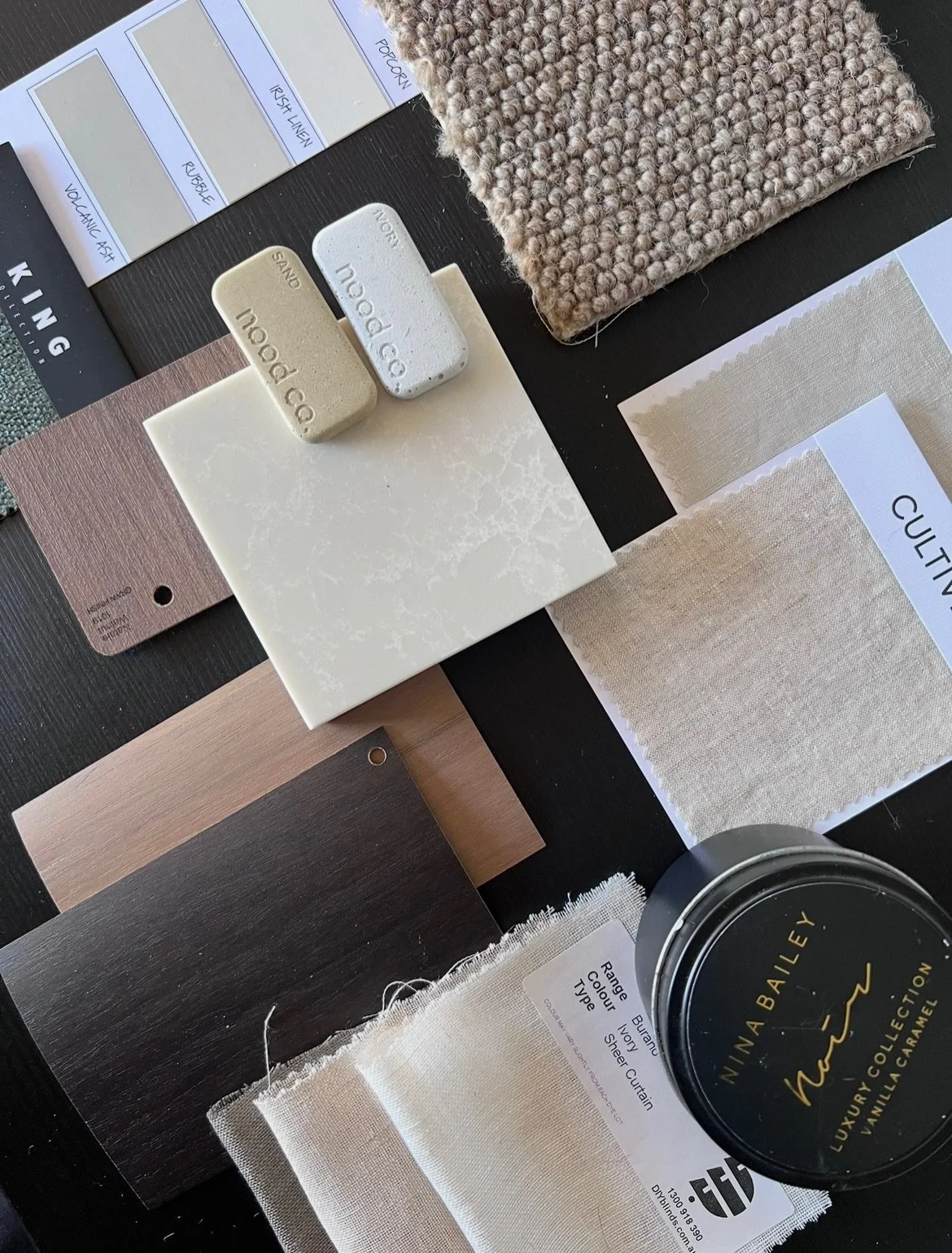 Flat lay: soft, grounded and tonal palette.

With dark timber, pale oak, warm stone, textured carpet, and soft neutral linens, this scheme leans on materiality as much as colour.

The variation in texture does most of the work here. The darker timber
