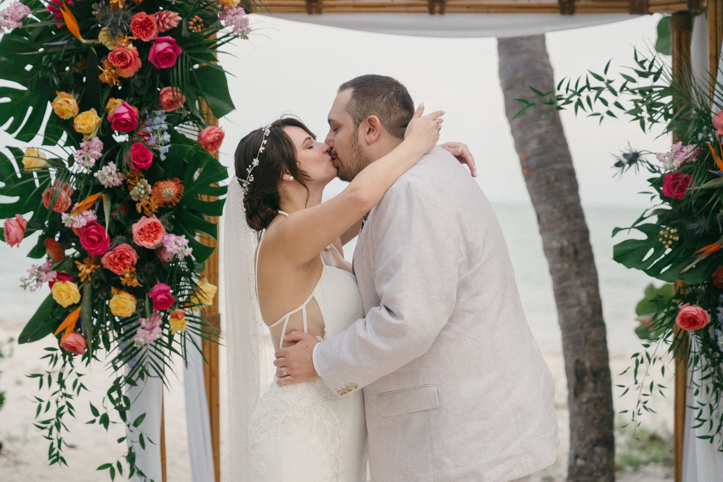Bride and groom sharing a kiss during an intimate beach wedding ceremony surrounded by their wedding party in Key West, Florida.