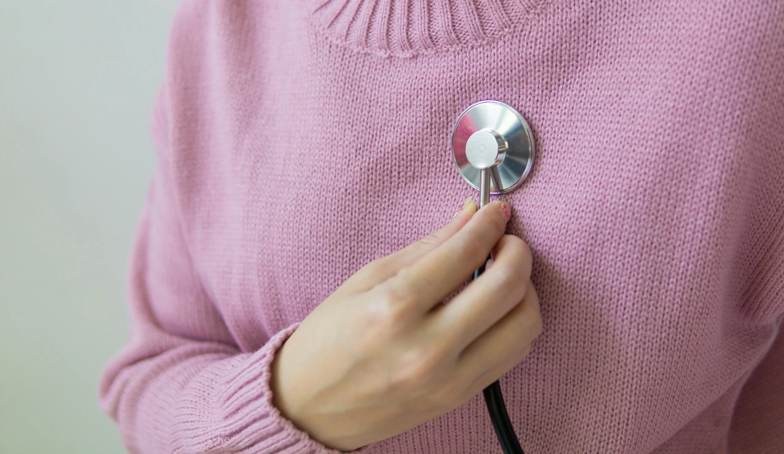 A woman using a stethoscope to herself