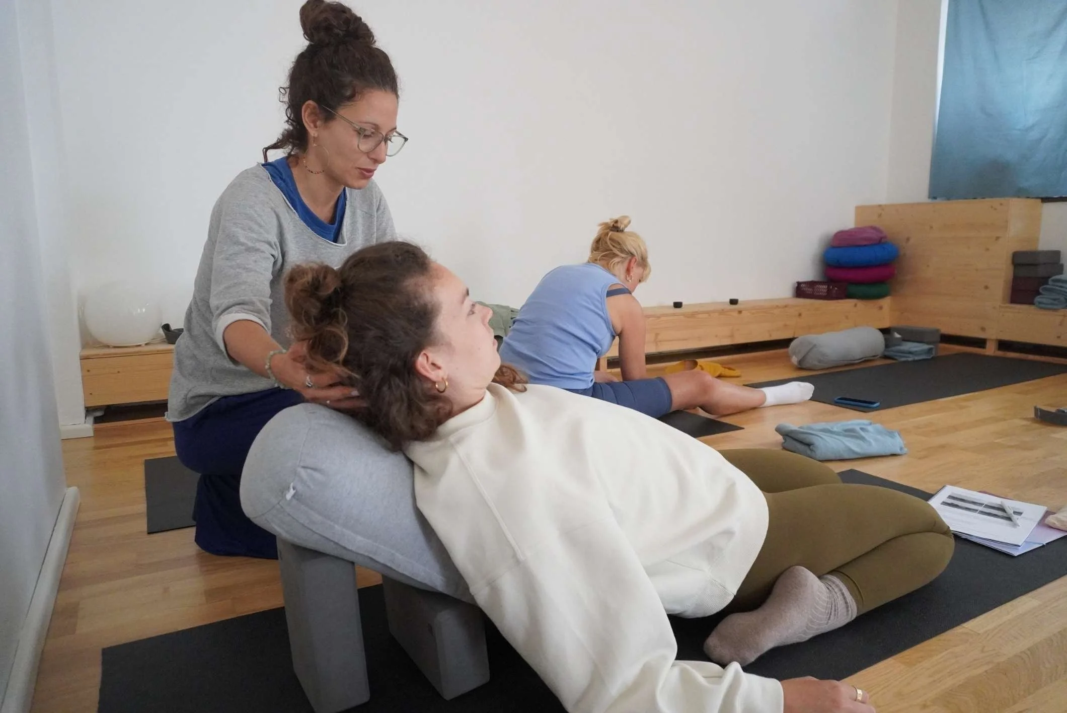 nikoleta nikisianli assistiert bei einer yin yoga position mit hilfsmitteln