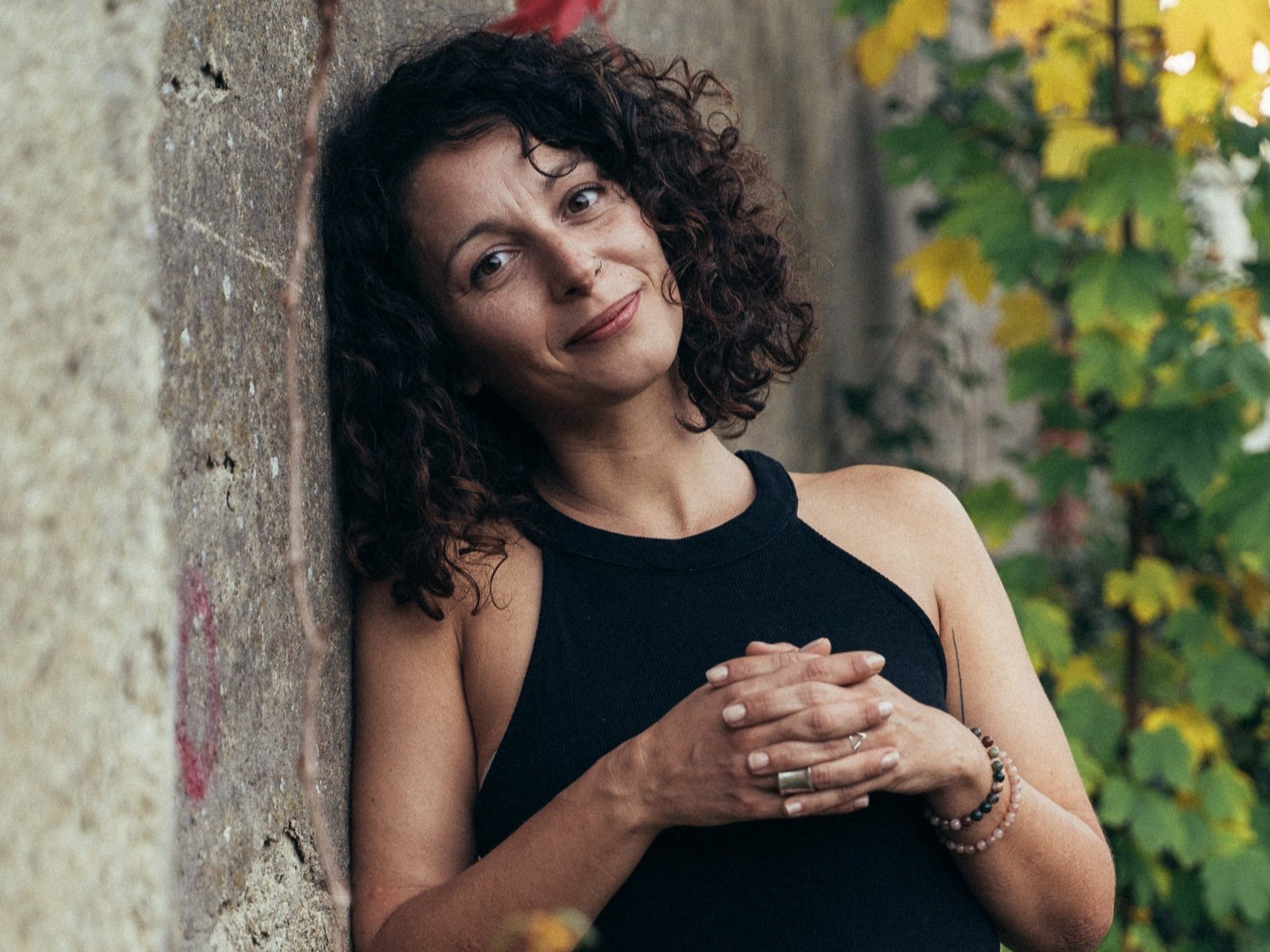 Nikoleta Nikisianli lehnt an Wand und gelbe Blumen im Hintergrund