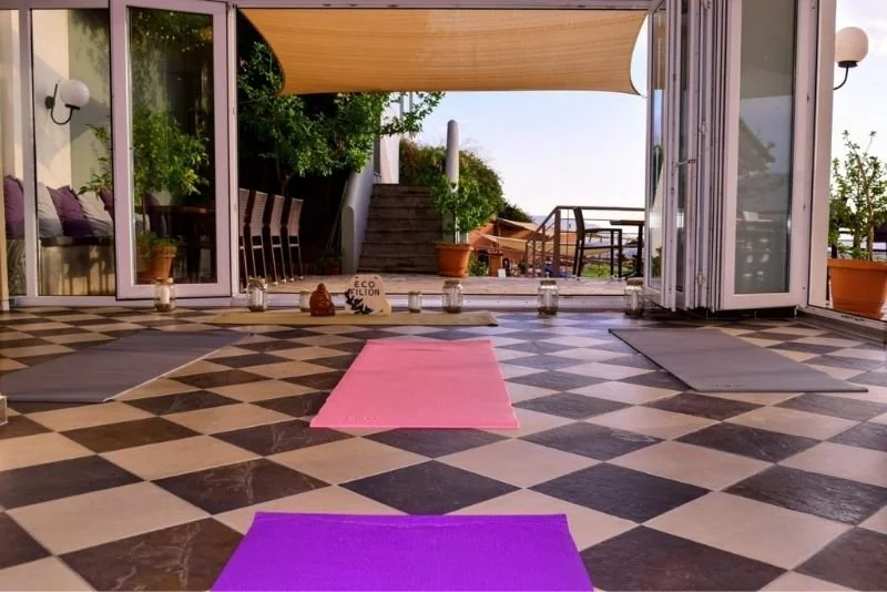 Ein Innenraum für Yin Yoga und dynamic flow Yoga mit einam schwarz-weißen Boden, bunten Yogamatten und einer großen Fensterfront 
