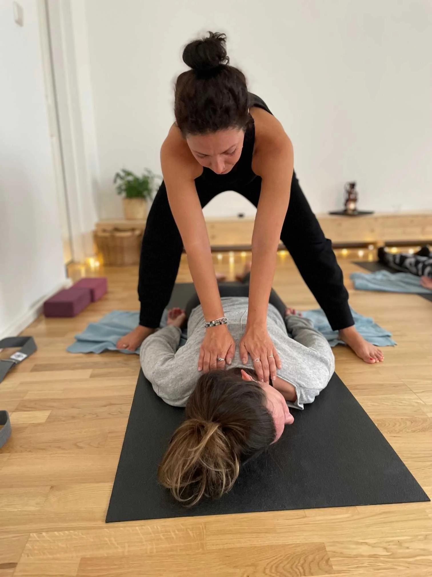 nikoleta assistiert einer teilnehmerin bei einer yin klasse durch sanften druck auf ruecken