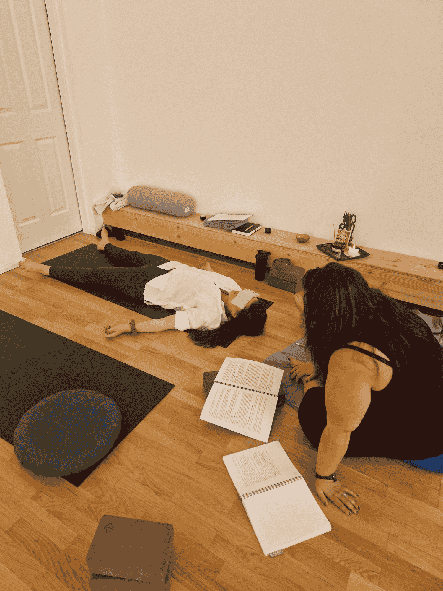 one participant lying on floor as another reads the yoga nidra script
