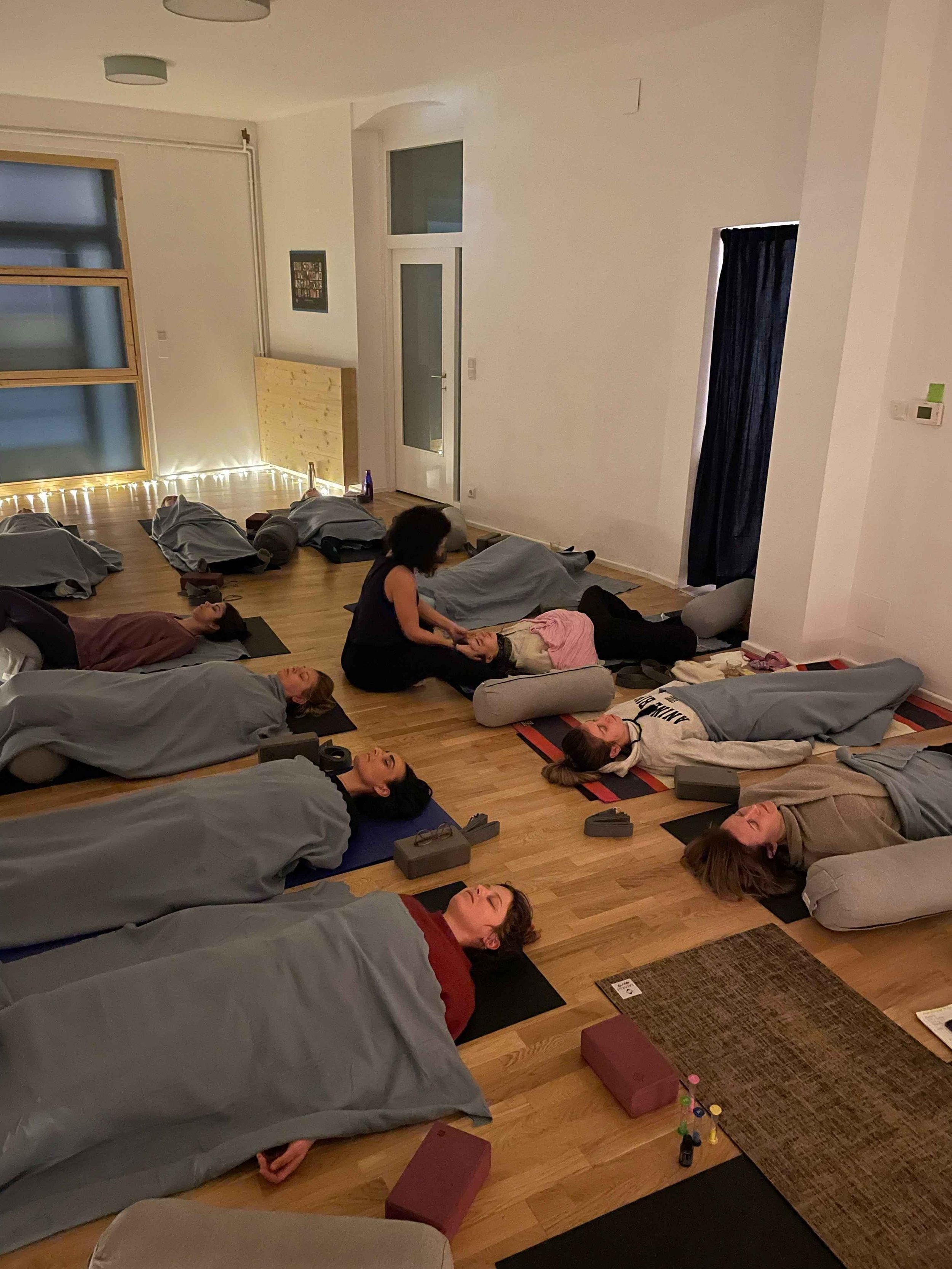nikoleta assistiert teilnehmender waehrend endentspannung einer yin yoga klasse