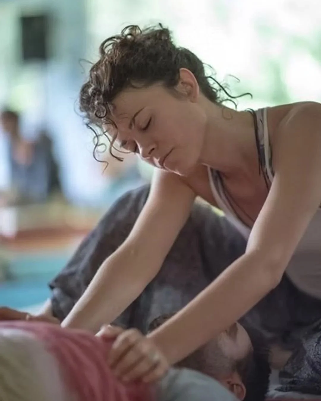 Elisabeth während einer Thai Bodywork session, massiert jemanden der am Boden liegt entlang des Brustkorbs