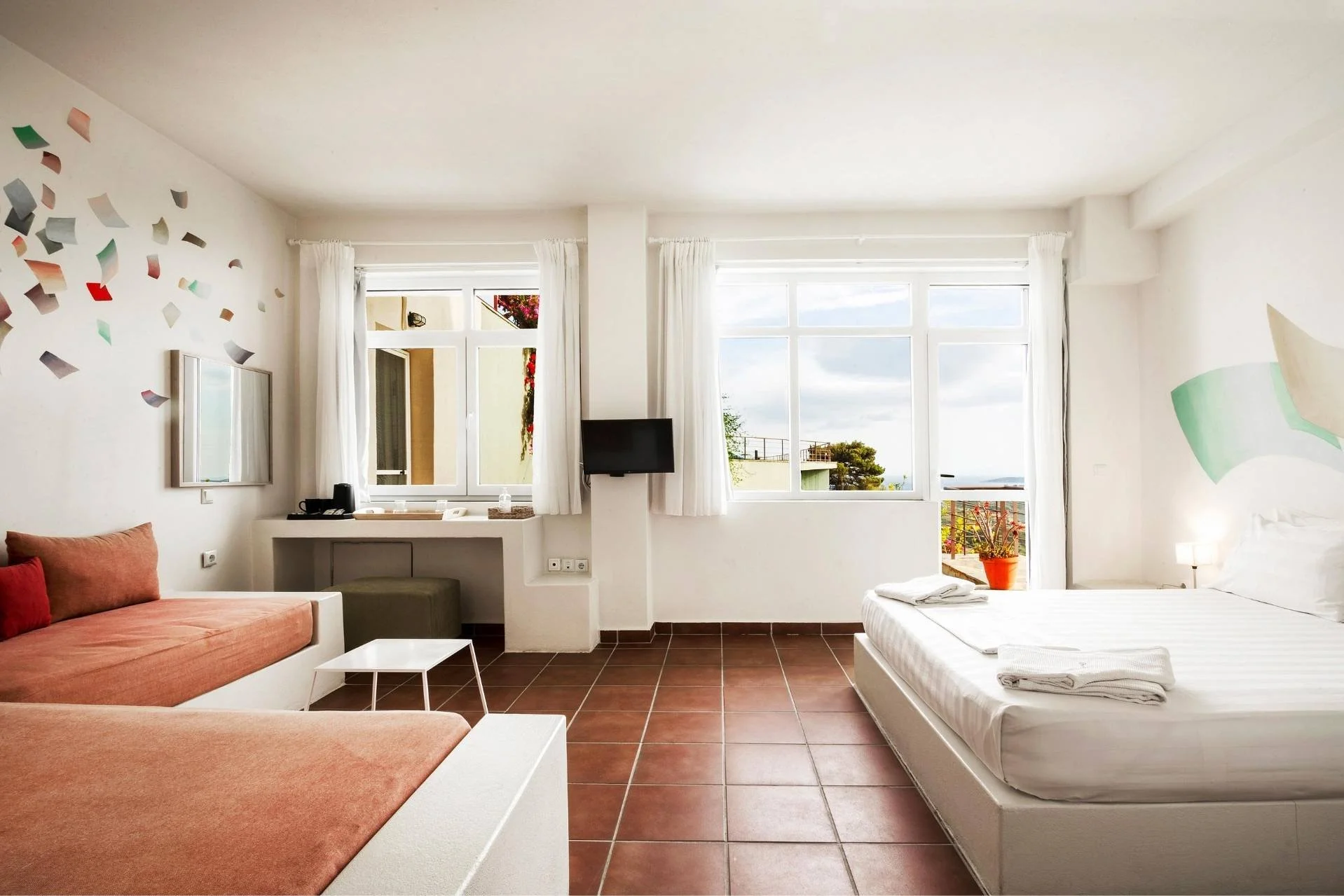 Ein Schlafzimmer mit einem Doppelbett und einem Ecksofa mit braunem Bezug, in der Flow and Yin Retreat Location in Griechenland
