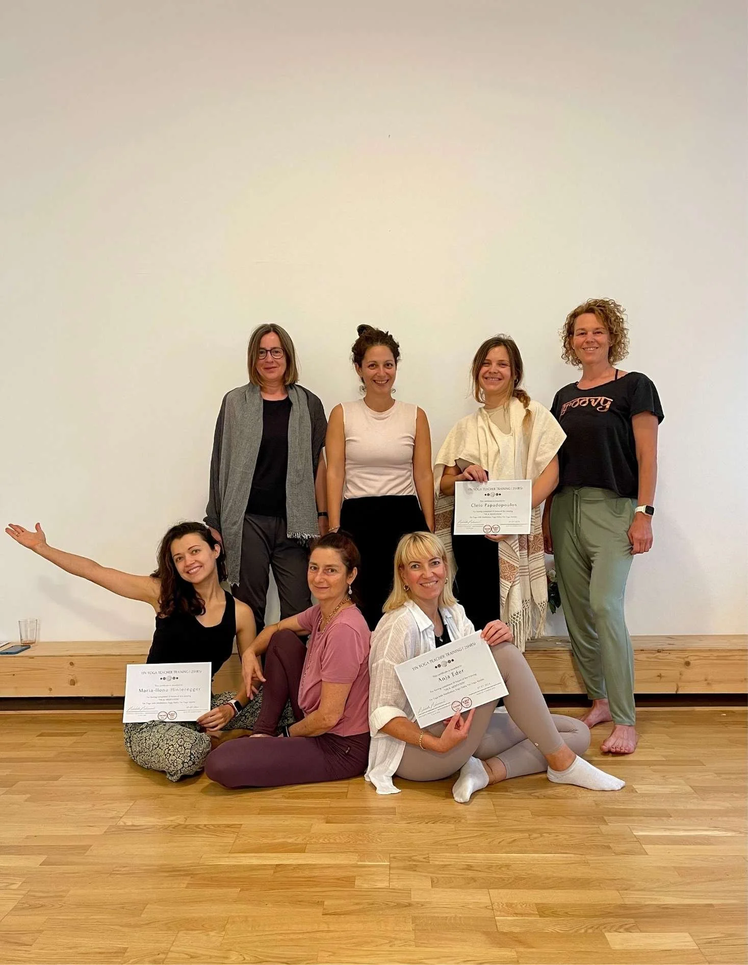 teilnehmerinnen und lehrerin von yin und yoga nidra ausbildung in kamera lächelnd mit ihren diplomen