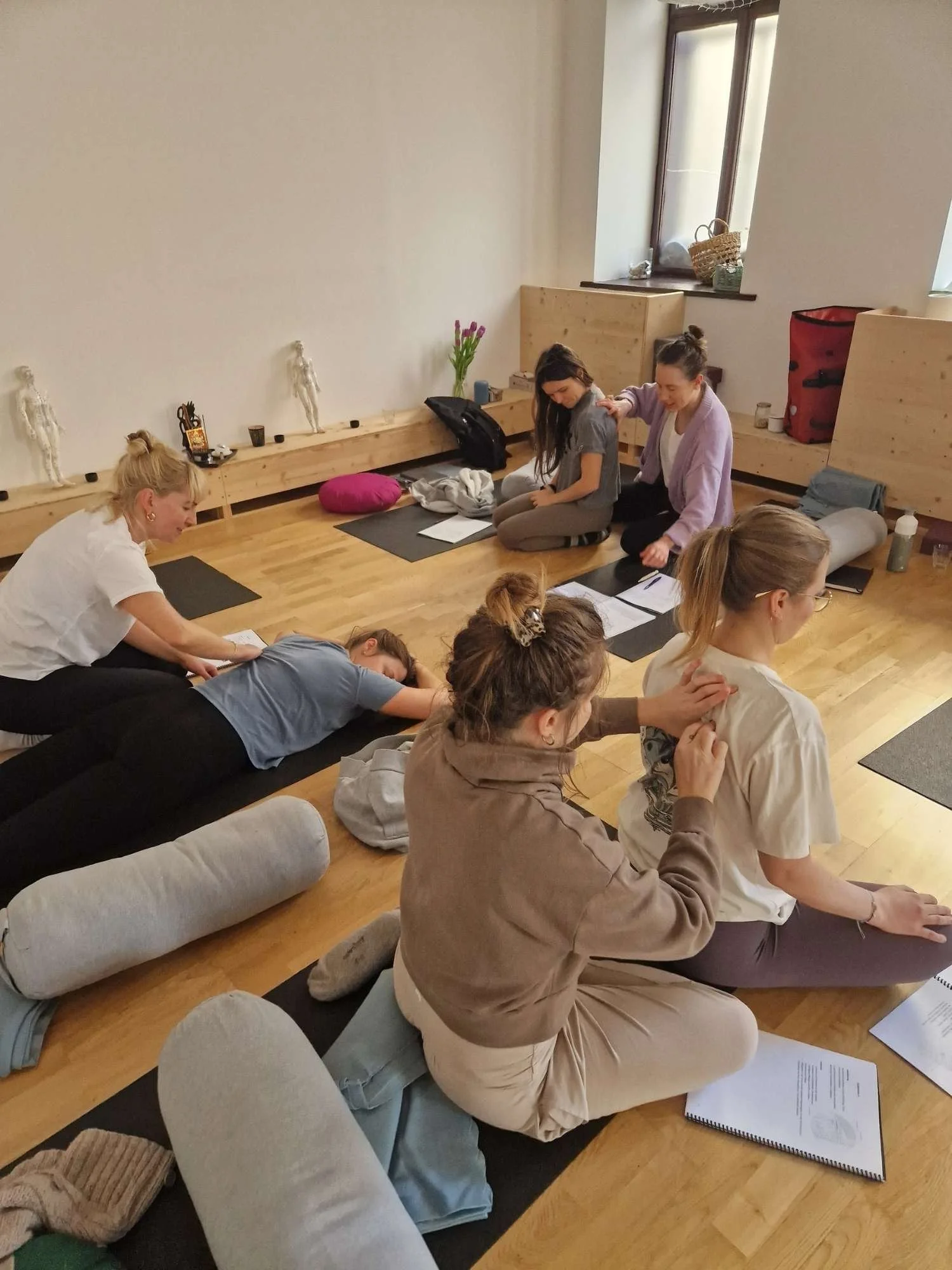 teilnehmende arbeiten in zweier gruppen um akupressurpunkt auf schulterblatt zu finden