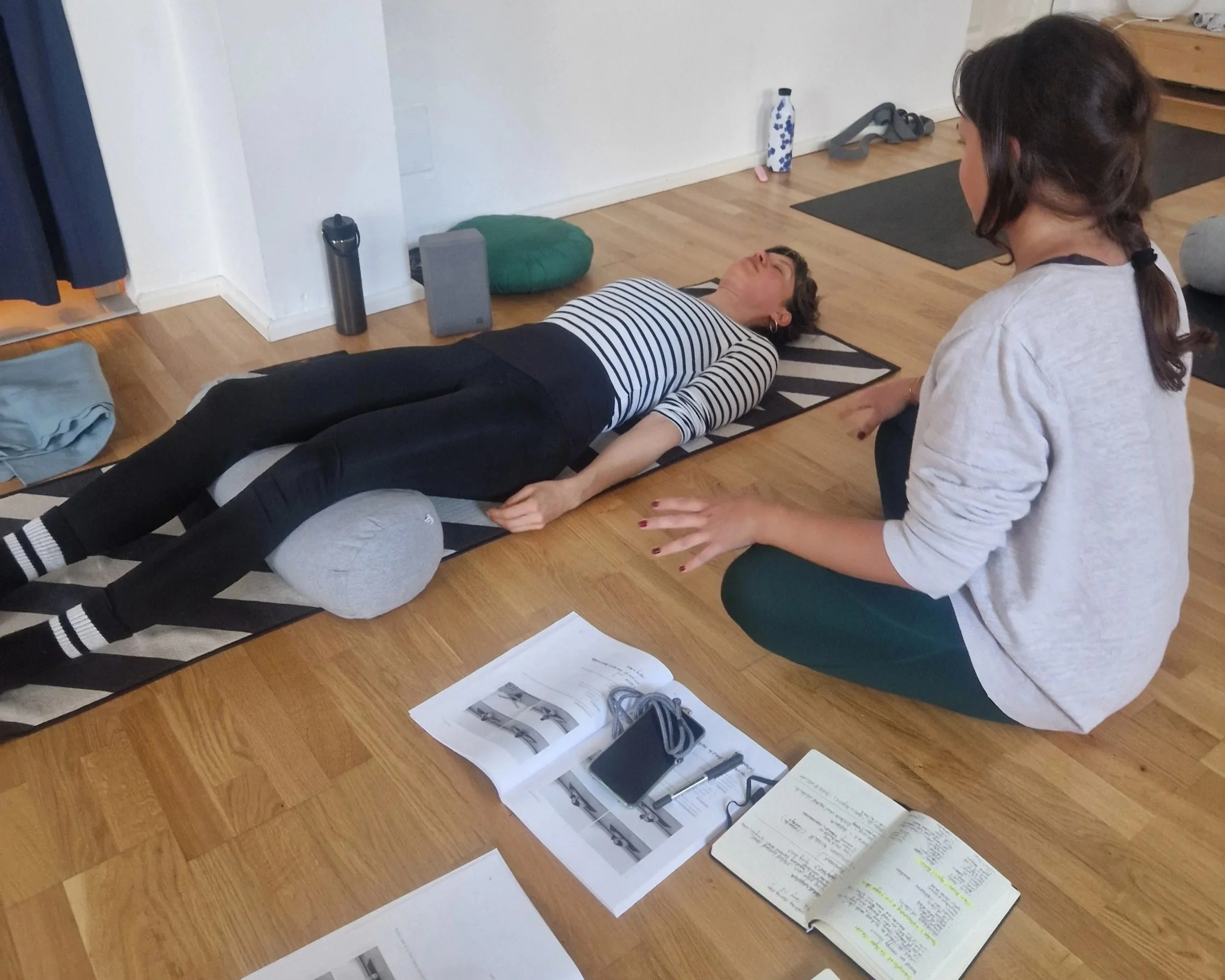 one student sitting and guiding the other student who islaying down