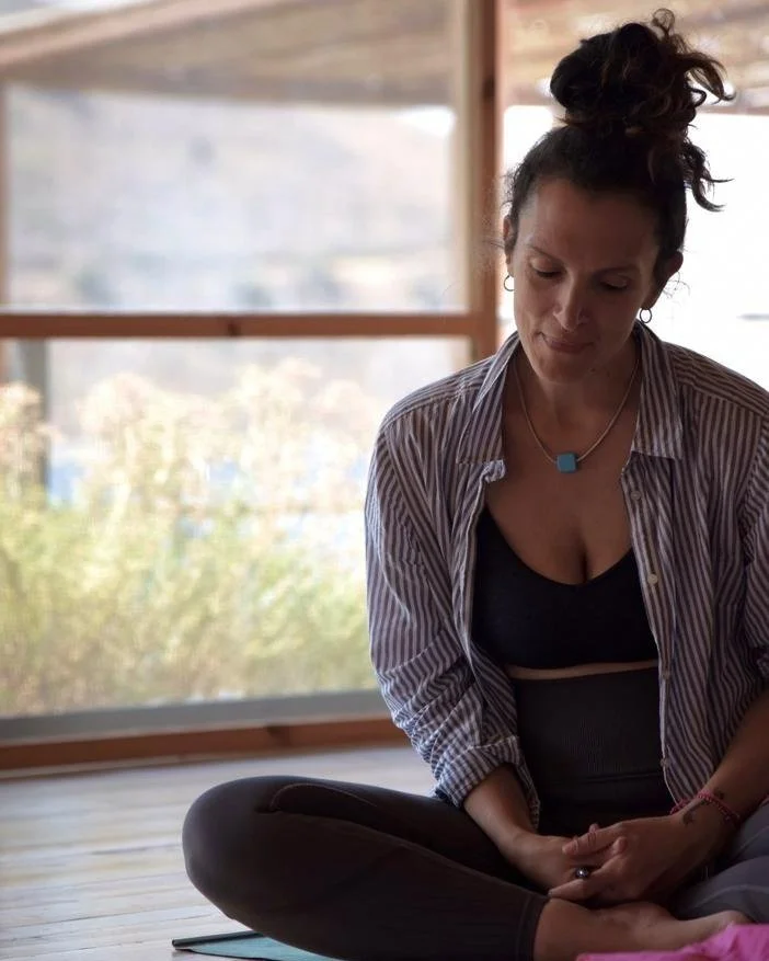 Vasiliki sitting in a yoga shala in front of big window