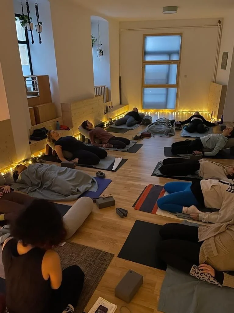 teilnehmende liegen in Rückenlage während Lehrerin vorne anleitet