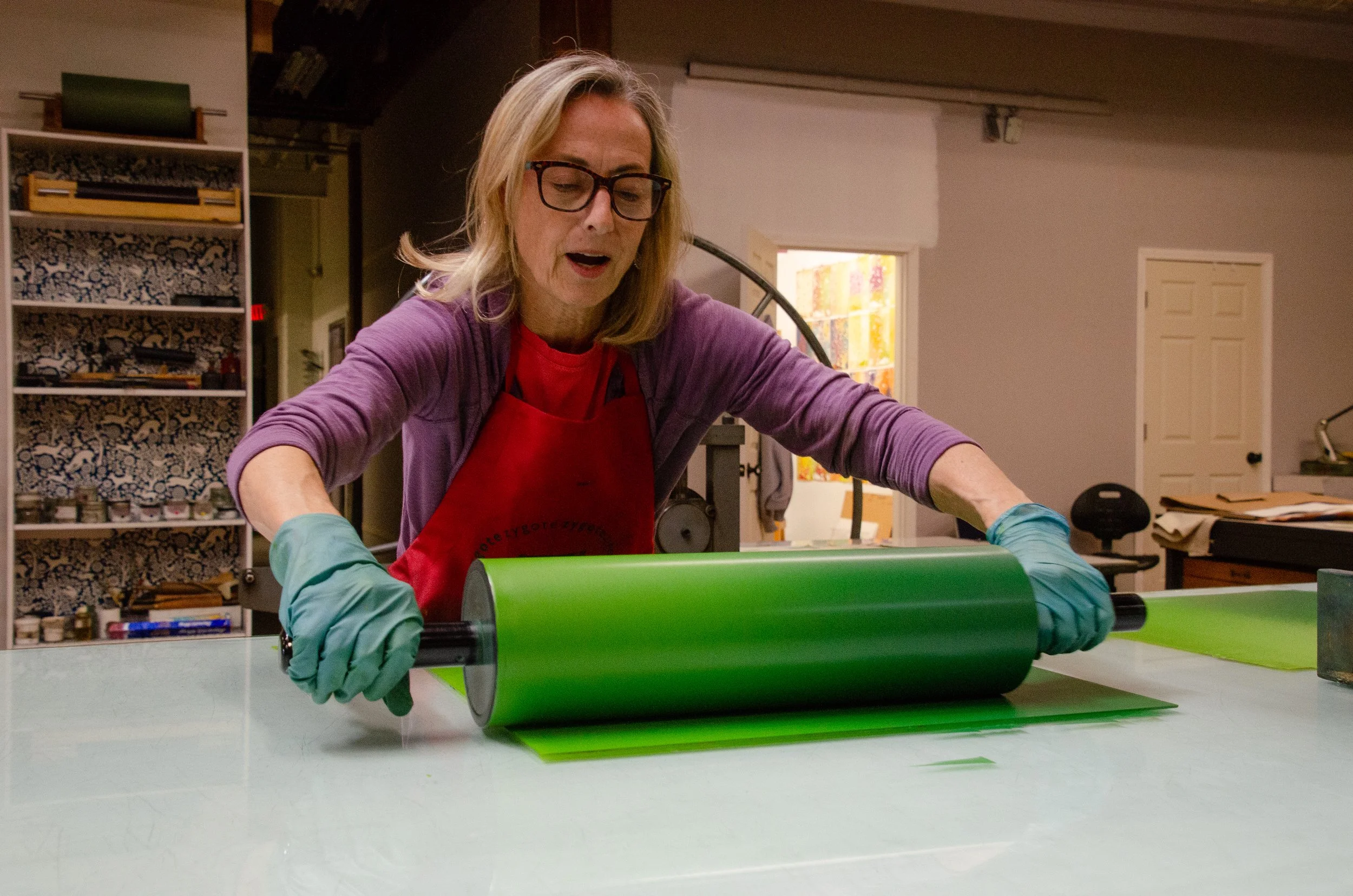 Artist Lisa Schonberg rolls green ink on a plate at Zygote Press