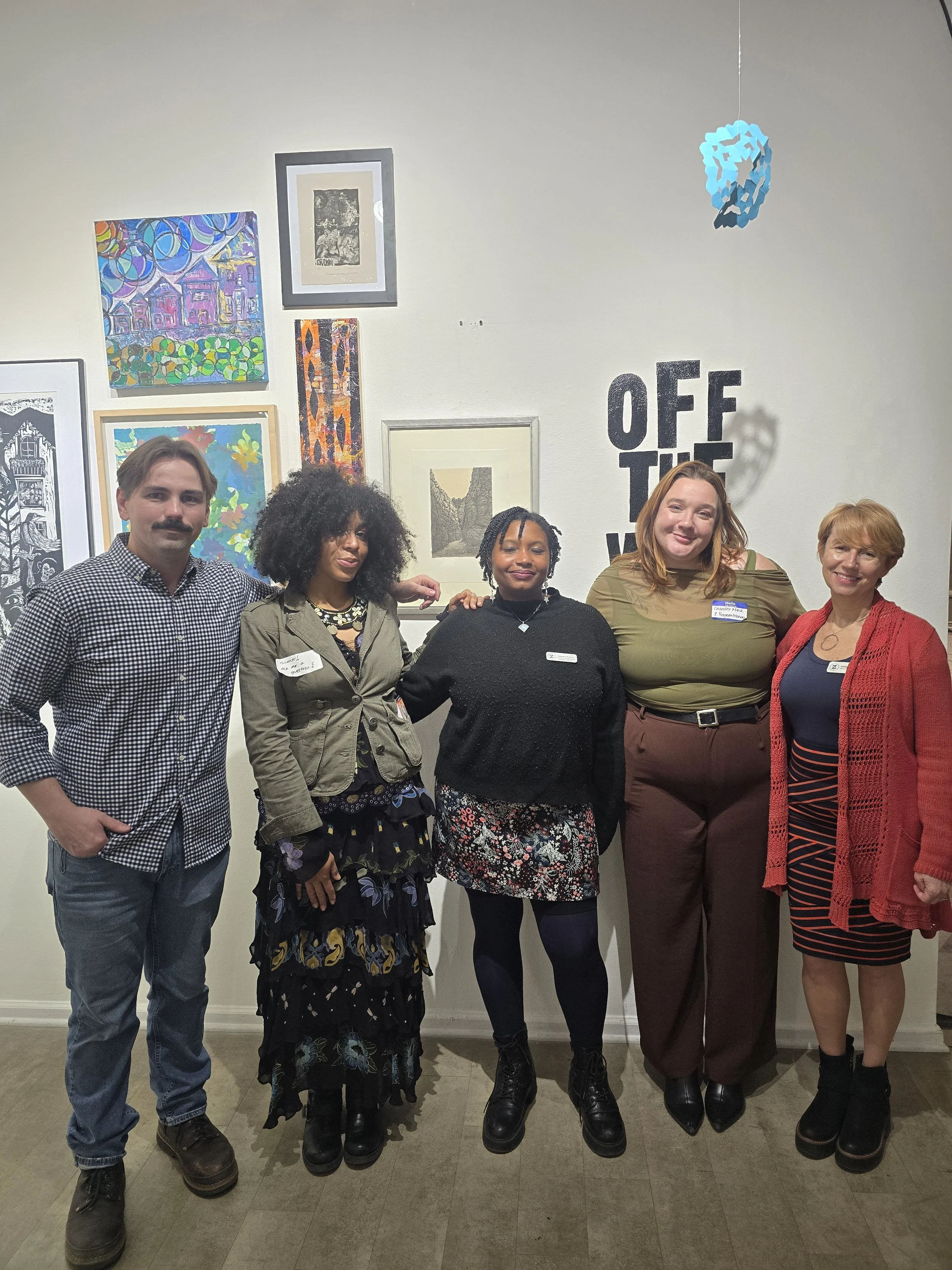 Five Zygote Press staff members pose for a photo in front of a wall of artwork.