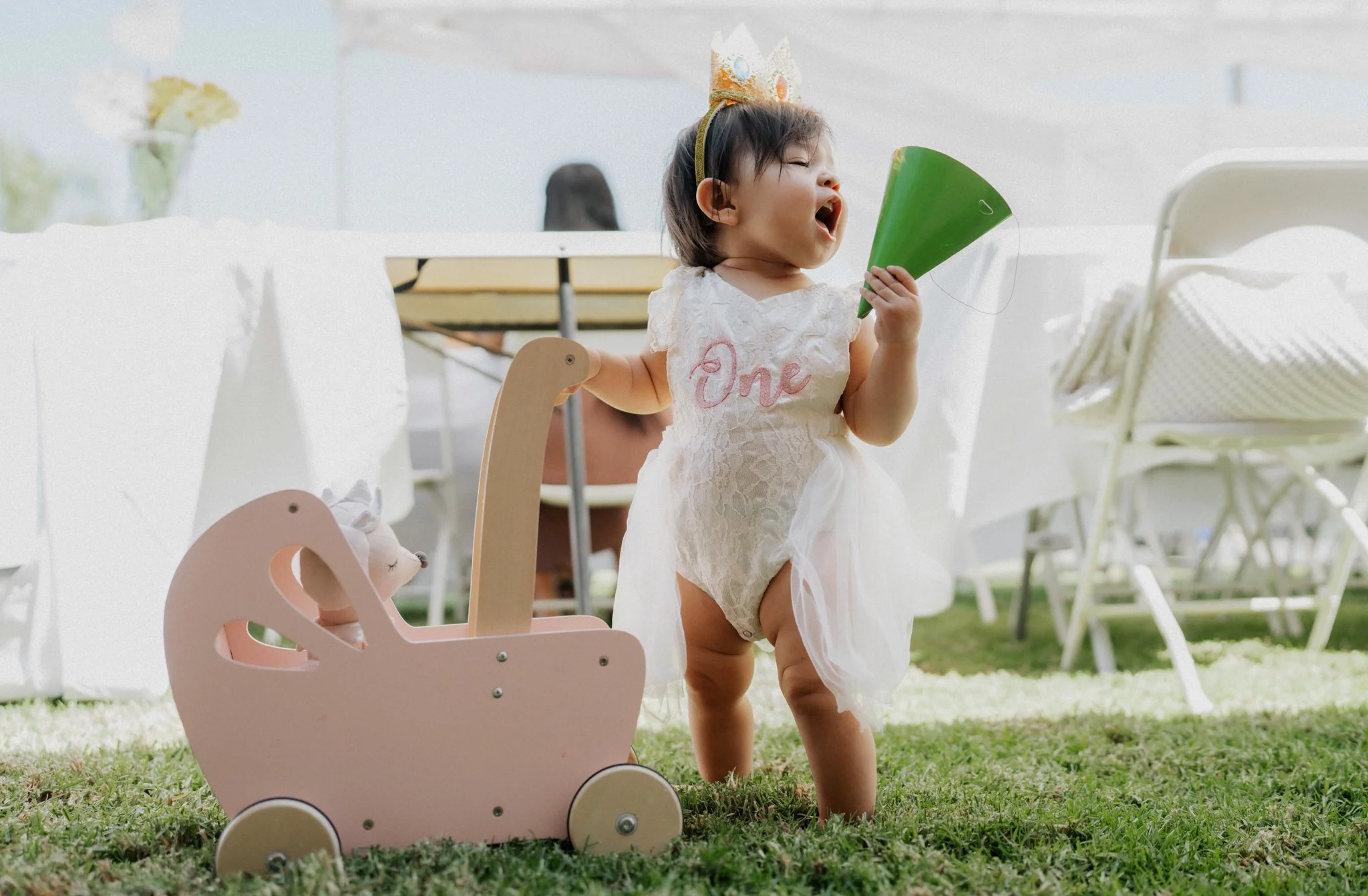 baby girl on her first birthday holding a birthday hat
