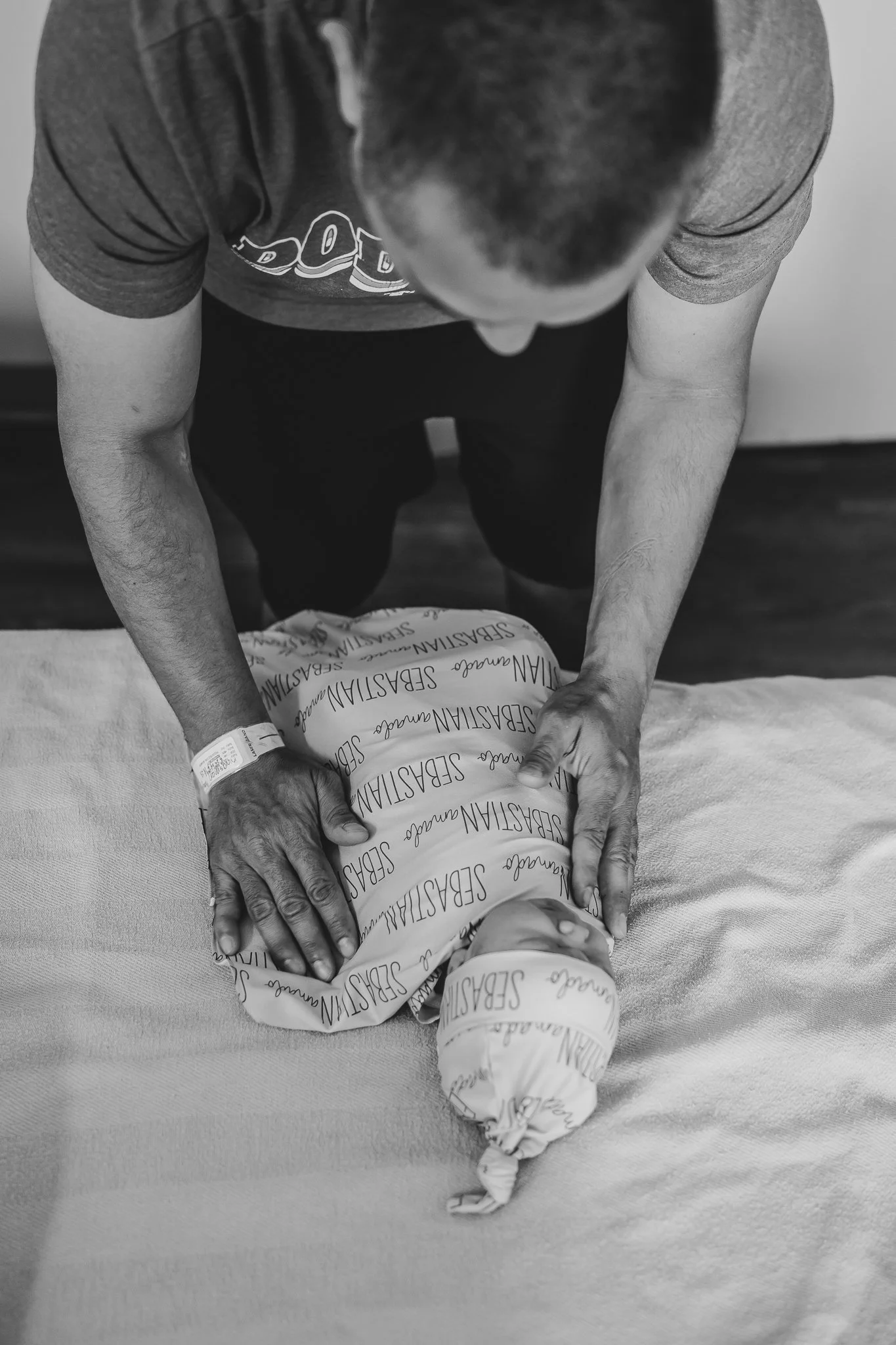 Father wrapping newborn baby boy in a blanket in hospital in California