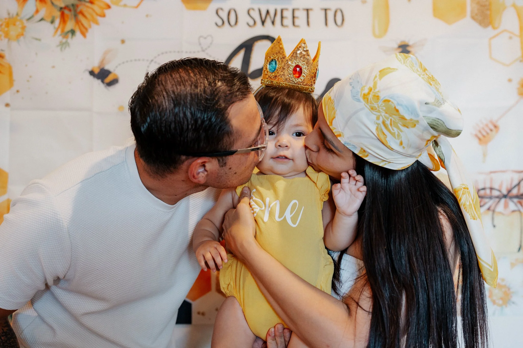 baby girl on her birthday kissed by her mom and dad