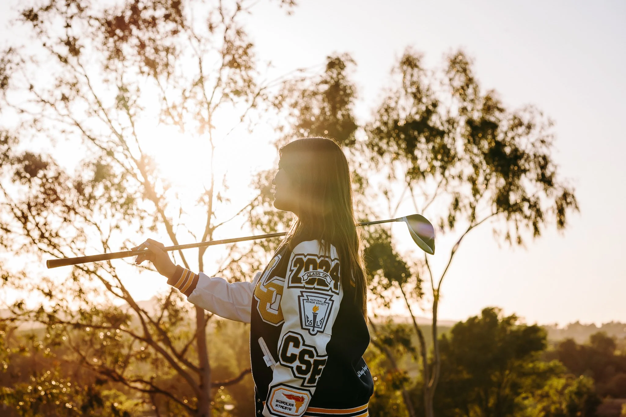 high school graduate with letterman jacket and golf club over shoulder side profile