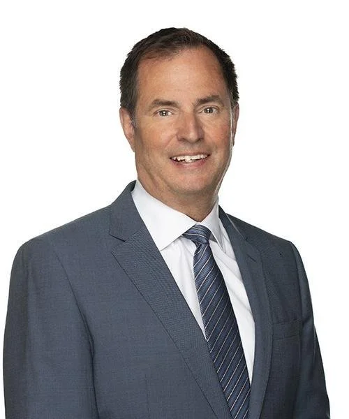 Smiling man in a suit and tie on a white background.