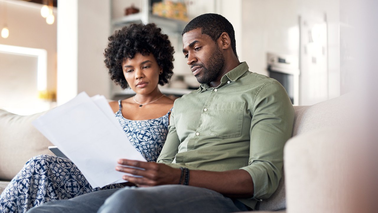 a couple sitting on a couch reviewing their taxes