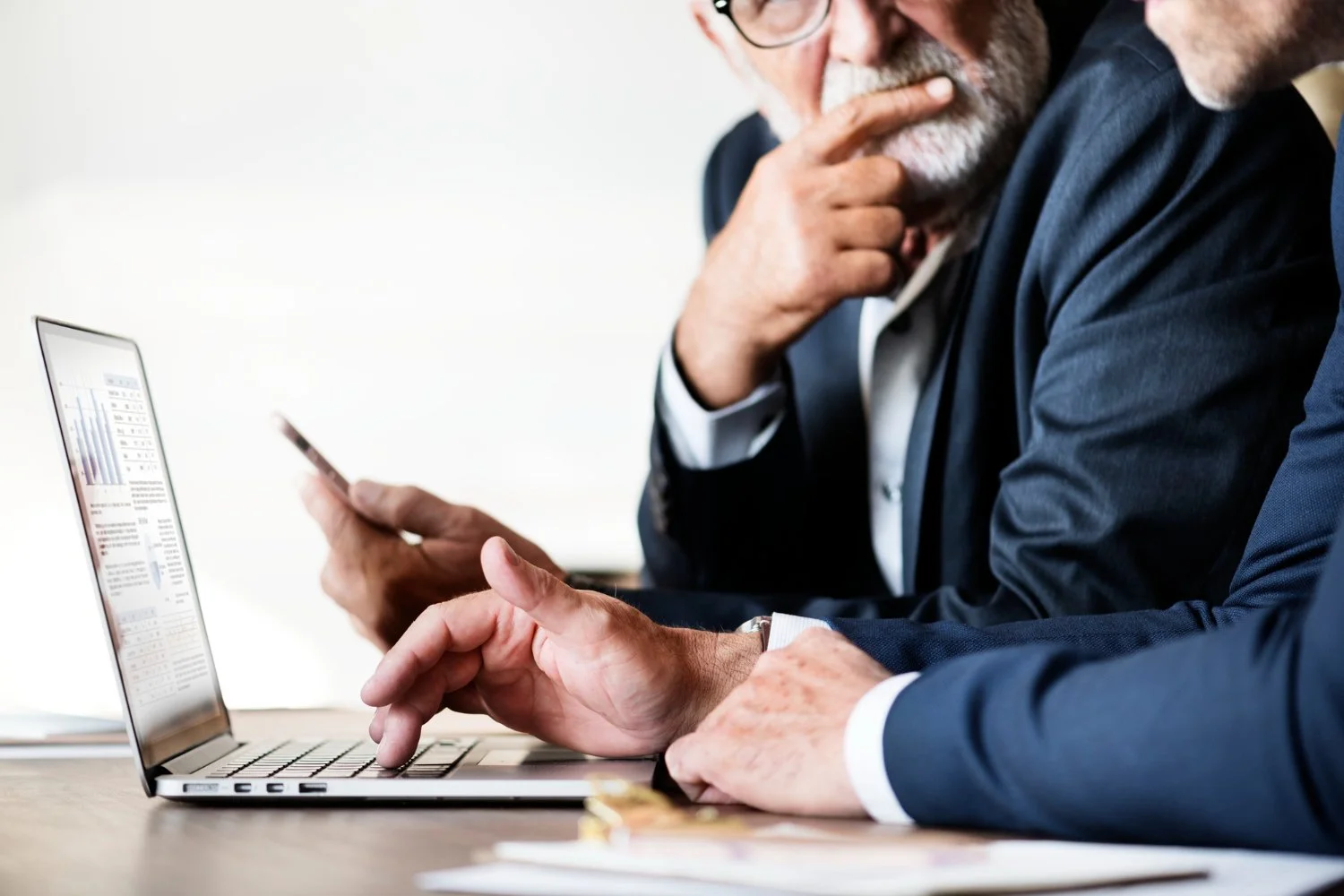 two men discussing financial matters sitting in front of a laptop screen