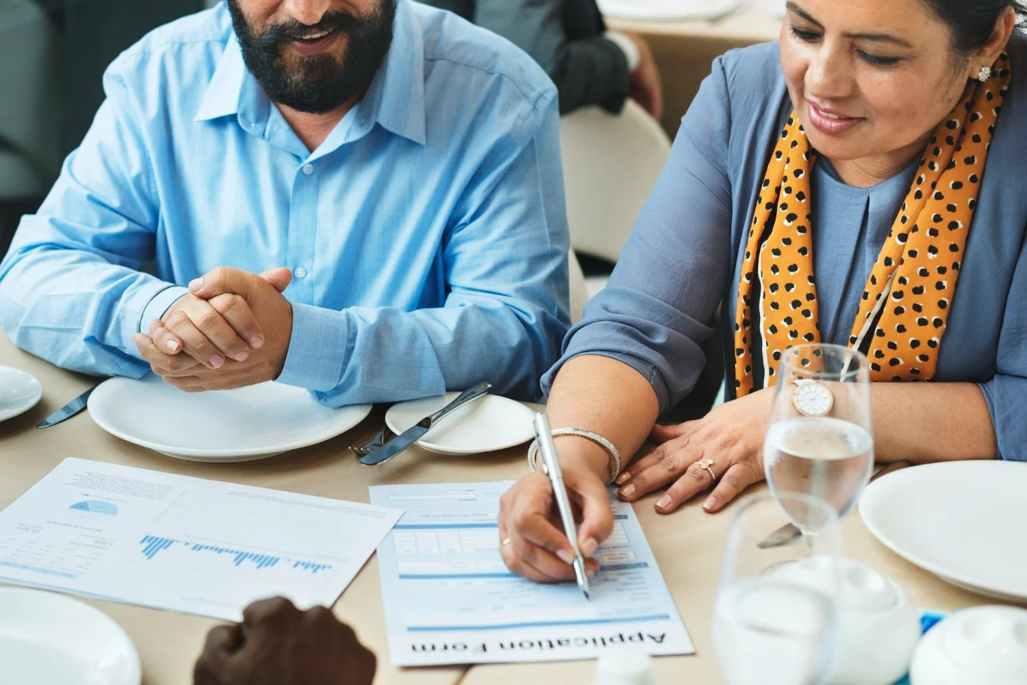 a couple sitting at a table discussing financial matters, on the table there are papers with charts