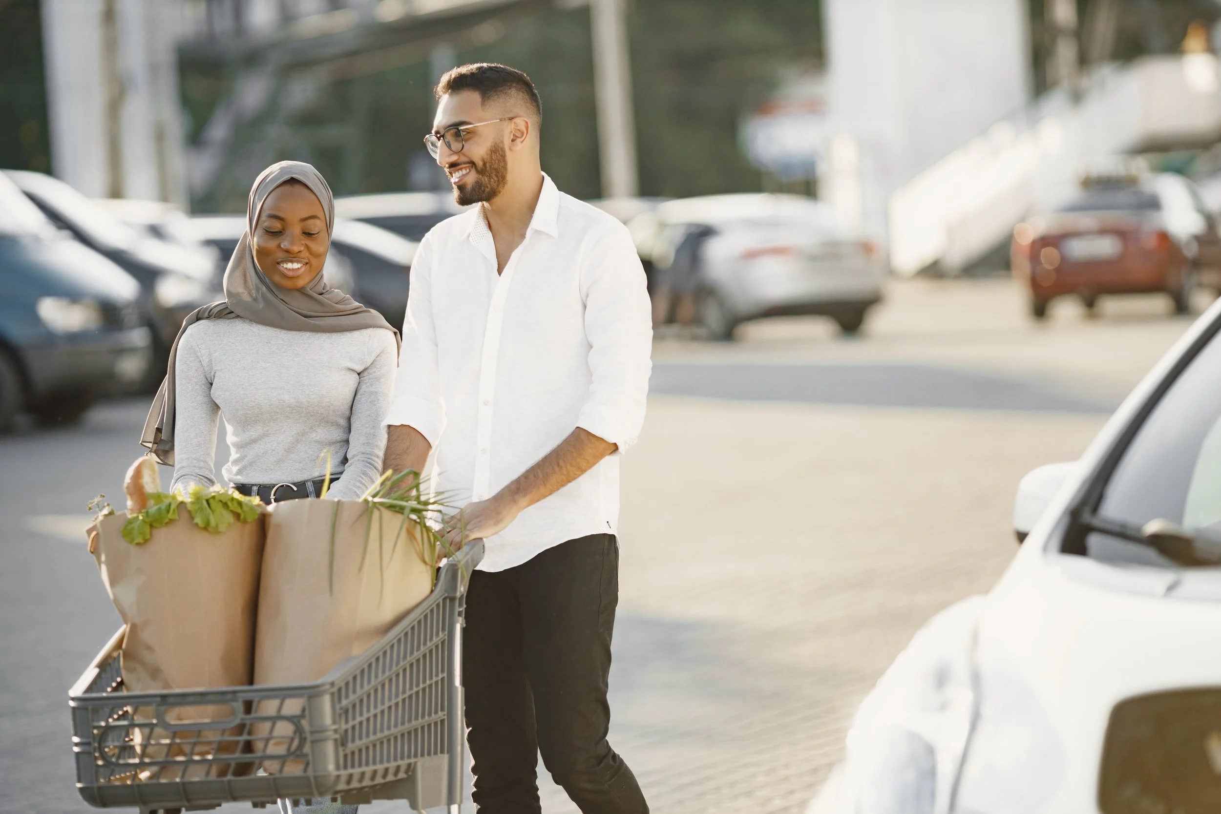 african arabian couple stands with groceries near electric car charging gas station
