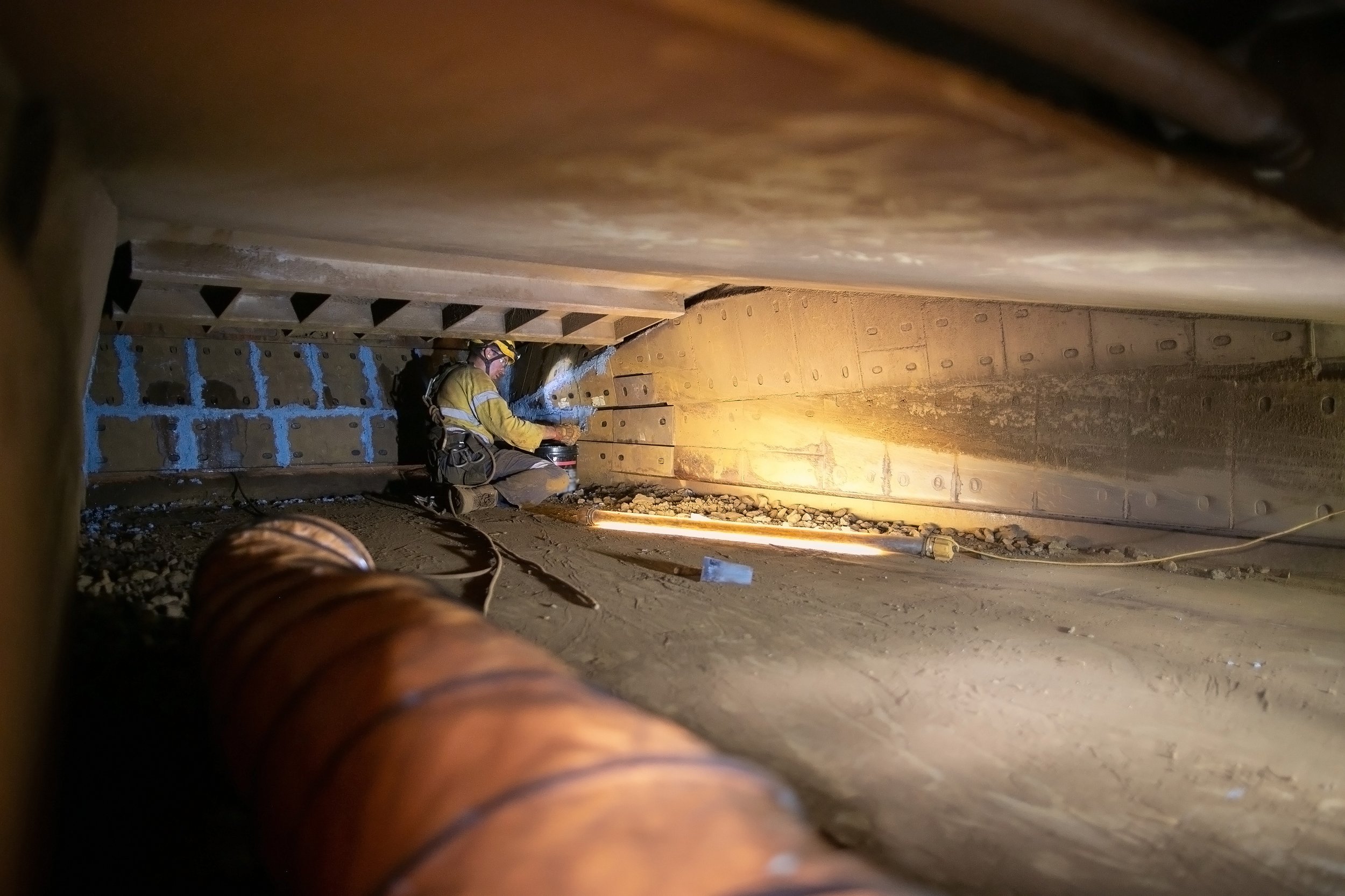 Worker performing maintenance inside a low-clearance confined space